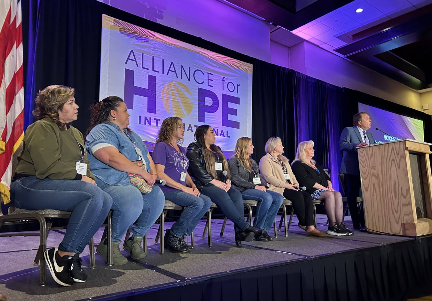 A group of people sitting on a stage and speaking to an audience
