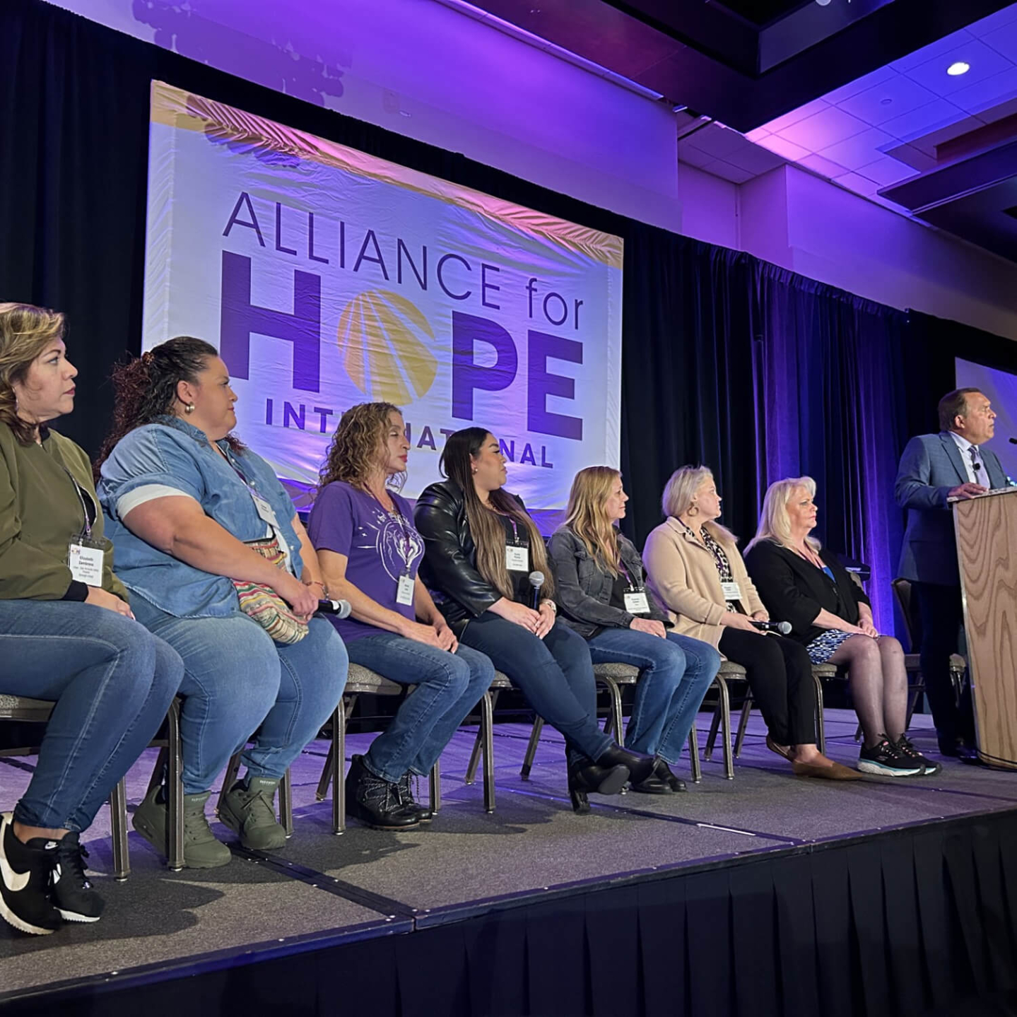 A group of people sitting on a stage and speaking to an audience